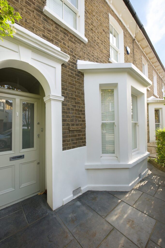 a white composite door in a porch on a house with a white bay window