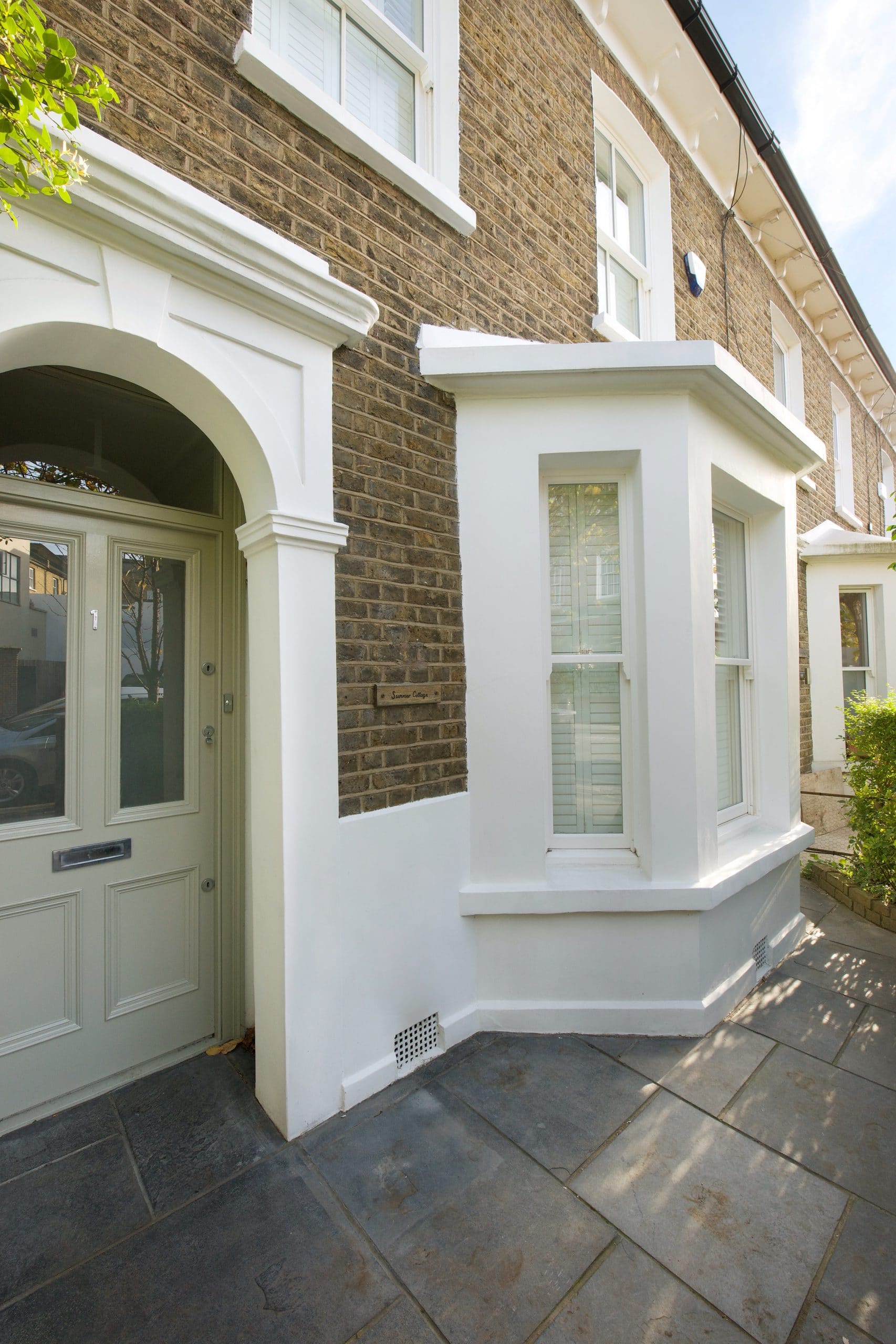 a white composite door in a porch on a house with a white bay window